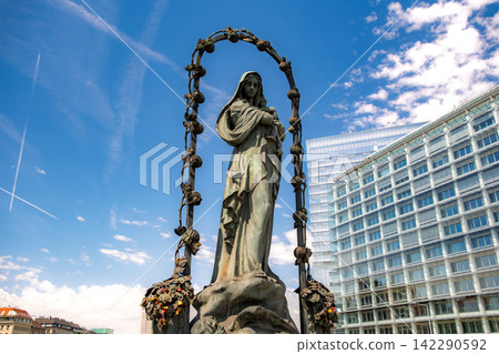 Vienna, Austria. A beautiful statue of the Virgin Mary standing on the Marienbrücke bridge over the Danube Canal, against a backdrop of blue skies. Vienna, Austria. A beautiful statue of the Virgin Mary standing on the Marienbrücke bridge over the Danube Canal, against a backdrop of blue skies. 142290592