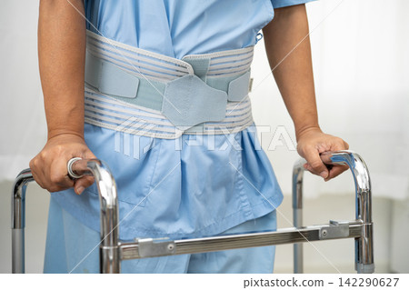 Asian lady patient wearing back pain support belt for orthopedic lumbar with walker. Asian lady patient wearing back pain support belt for orthopedic lumbar with walker. 142290627