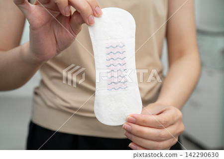 Asian woman holding sanitary napkin pad for hygiene menstrual period cycle protection. 142290630