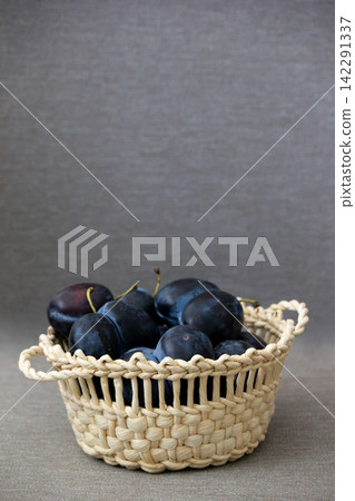 Fresh ripe blue plums in wicker basket over linen background Fresh ripe blue plums in wicker basket over linen background 142291337