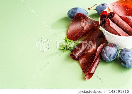 Homemade plum pastila rolls with fruit on soft green background Homemade plum pastila rolls with fruit on soft green background 142291810