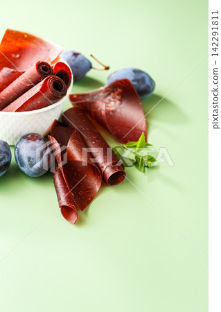 Homemade plum pastila rolls with fruit on soft green background Homemade plum pastila rolls with fruit on soft green background 142291811
