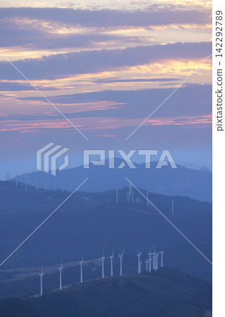 Wind turbines generating clean energy during a colorful sunset over mountains Wind turbines generating clean energy during a colorful sunset over mountains 142292789