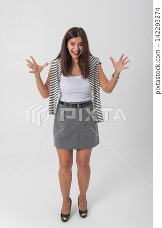 Young woman standing full body with arms raised, smiling and surprised in a joyful, excited reaction on white studio background, expressing astonishment and positivity Young woman standing full body with arms raised, smiling and surprised in a joyful, excited reaction on white studio background, expressing astonishment and positivity 142293274