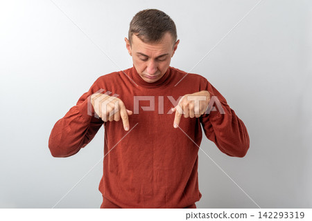 Man with a serious expression pointing both index fingers downwards, indicating location or highlighting important content in a space below the subject Man with a serious expression pointing both index fingers downwards, indicating location or highlighting important content in a space below the subject 142293319