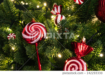 Red candy ornaments on illuminated Christmas tree Red candy ornaments on illuminated Christmas tree 142293330