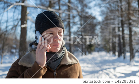 Young man talking on smartphone outdoors in winter park Young man talking on smartphone outdoors in winter park 142293381
