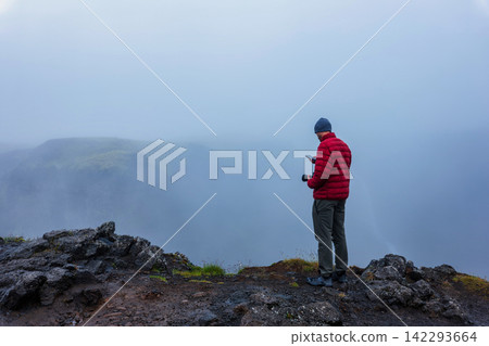 Hiker in Red Jacket Standing on Rocky Mountain Peak Iceland Hiker in Red Jacket Standing on Rocky Mountain Peak Iceland 142293664