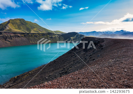 Turquoise crater lake with moss-covered mountain in Iceland volcanic landscape Turquoise crater lake with moss-covered mountain in Iceland volcanic landscape 142293675