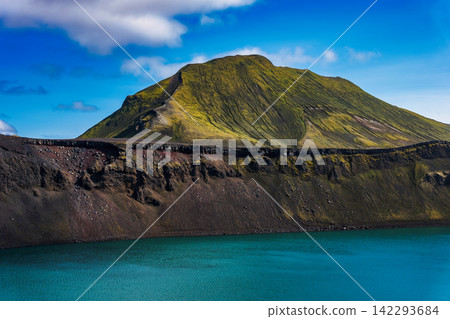 Moss-covered volcanic mountain and turquoise glacial lake Iceland Moss-covered volcanic mountain and turquoise glacial lake Iceland 142293684