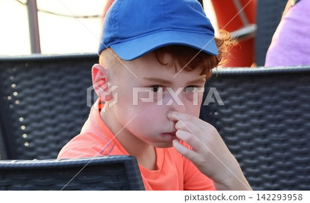 close-up shot of a little boy covering his nose because something smells bad there. close-up shot of a little boy covering his nose because something smells bad there. 142293958