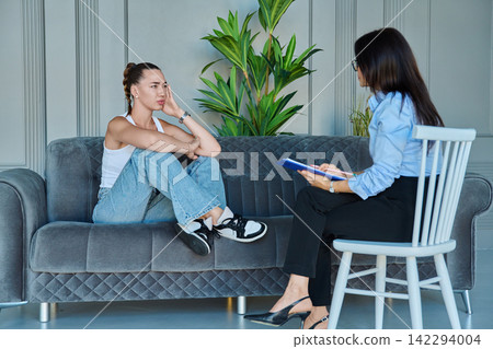 Young woman having consultation with female therapist on sofa Young woman having consultation with female therapist on sofa 142294004