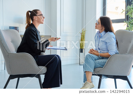 Female psychologist consulting attentive female client during therapy session 142294015