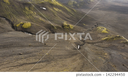 Aerial view of volcanic valley with moss-covered mountains and meltwater stream, Iceland Aerial view of volcanic valley with moss-covered mountains and meltwater stream, Iceland 142294450