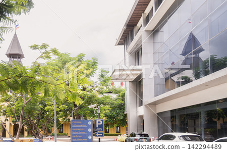 A striking modern glass facade reflecting the iconic historic yellow Dome Building at Thammasat University campus in Bangkok, Thailand. A striking modern glass facade reflecting the iconic historic yellow Dome Building at Thammasat University campus in Bangkok, Thailand. 142294489