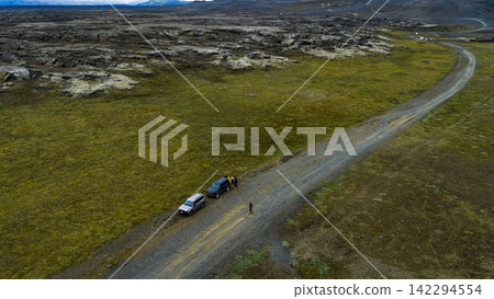 Aerial view of gravel road with parked vehicles and hikers, ytra Iceland Aerial view of gravel road with parked vehicles and hikers, ytra Iceland 142294554