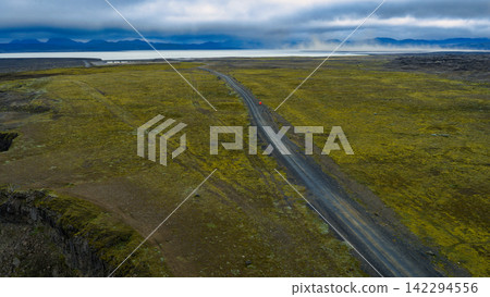 Aerial view of Route 1 through moss-covered lava fields with distant mountains, ytra Iceland Aerial view of Route 1 through moss-covered lava fields with distant mountains, ytra Iceland 142294556
