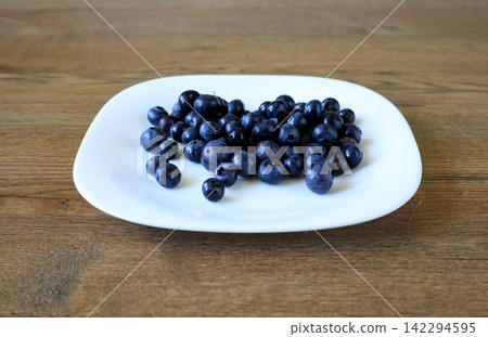 Bilberries from Forest Arranged on White Plate Sitting on Wooden Surface 142294595