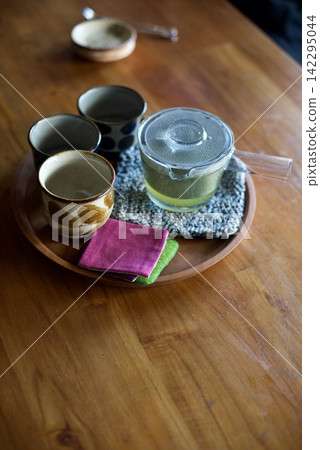 A teapot and teacup set on a round tray. A teapot and teacup set on a round tray. 142295044