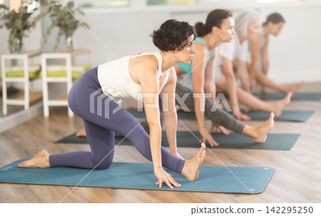 Group of women in activewear doing stretching exercises during training yoga in sports club Group of women in activewear doing stretching exercises during training yoga in sports club 142295250