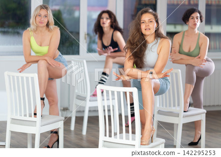 Putting foot hand on seat of chair, girl improvises, perform lap dance during group master class Putting foot hand on seat of chair, girl improvises, perform lap dance during group master class 142295253