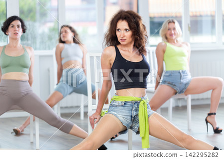 Sitting on chair, girl with long hair train to perform lap dance, interacting with imaginary partner 142295282