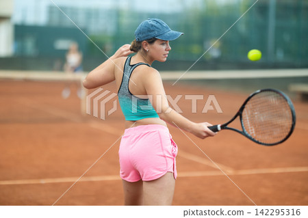 Young woman making serve while playing tennis Young woman making serve while playing tennis 142295316