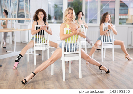 Expressive blonde in heels performing burlesque choreography with chair Expressive blonde in heels performing burlesque choreography with chair 142295390