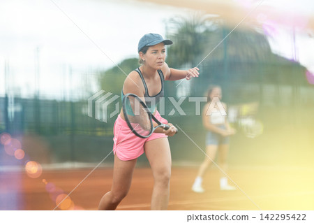 Two young women playing doubles tennis Two young women playing doubles tennis 142295422