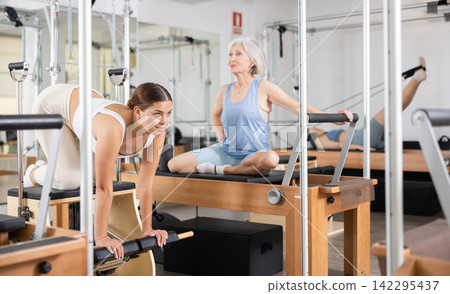 Young girl exercising on wunda chair in pilates studio Young girl exercising on wunda chair in pilates studio 142295437