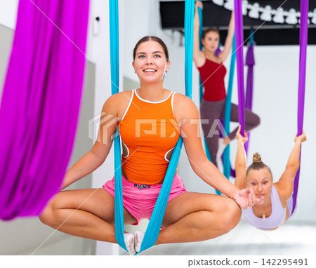 Girl doing Baddha Konasana asana in suspended hammock with hands in mudra Girl doing Baddha Konasana asana in suspended hammock with hands in mudra 142295491