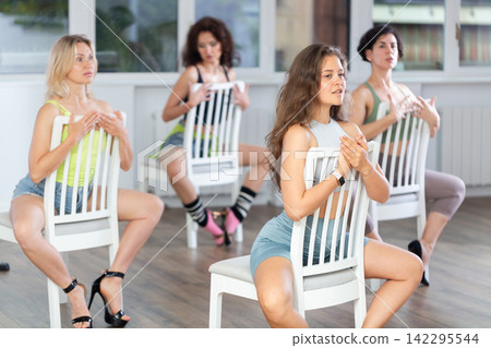Group of women in high heels rehearsing dance while sitting on chair Group of women in high heels rehearsing dance while sitting on chair 142295544