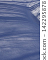 Blue shadow patterns stretching across the snow surface 142295878