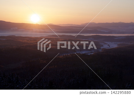 The rising sun and morning mist flowing through the snowy valley. The rising sun and morning mist flowing through the snowy valley. 142295880
