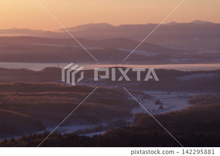 Mountain ranges shrouded in the morning glow and snow-covered fields Mountain ranges shrouded in the morning glow and snow-covered fields 142295881