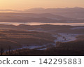 A forest of frost-covered trees and snow-covered farmland, shining in the morning sun. 142295883