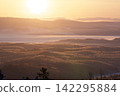 A snow-covered valley shrouded in golden morning mist. 142295884