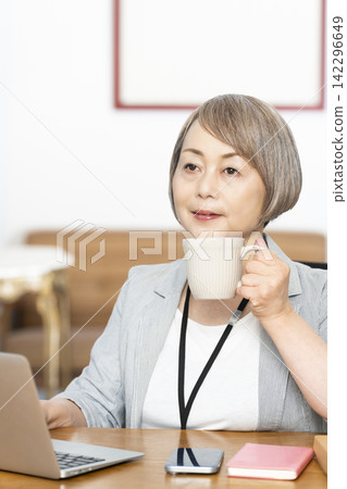 Senior woman drinking coffee while working in the office Senior woman drinking coffee while working in the office 142296649