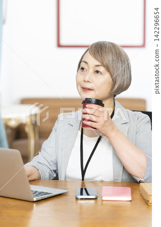 Senior woman drinking coffee while working in the office Senior woman drinking coffee while working in the office 142296654