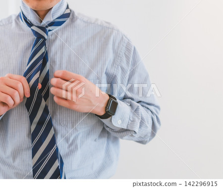A scene of a male business person getting ready to go to work, putting on a tie. A scene of a male business person getting ready to go to work, putting on a tie. 142296915