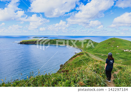 Tourists enjoy the spectacular scenery at Cape Gorota in Rishiri-Rebun-Sarobetsu National Park, where clear blue skies and lush green hills stretch out. Tourists enjoy the spectacular scenery at Cape Gorota in Rishiri-Rebun-Sarobetsu National Park, where clear blue skies and lush green hills stretch out. 142297184