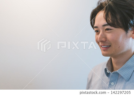 A smiling 20-something businessman's profile as he expands his copy space. A smiling 20-something businessman's profile as he expands his copy space. 142297205