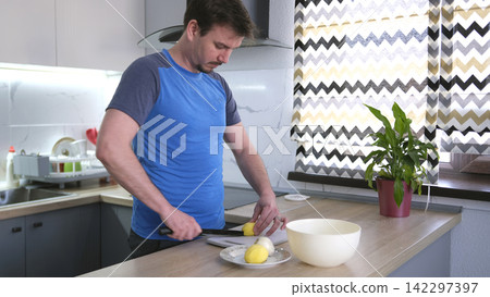 A young chef cuts raw potatoes. The process of cooking fried potatoes. A guy cooks a delicious dinner for his boyfriend A young chef cuts raw potatoes. The process of cooking fried potatoes. A guy cooks a delicious dinner for his boyfriend 142297397