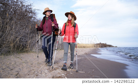 Two young students are walking along the beach. The wanderers travel the world together. Lesbian couple on a romantic date Two young students are walking along the beach. The wanderers travel the world together. Lesbian couple on a romantic date 142298122