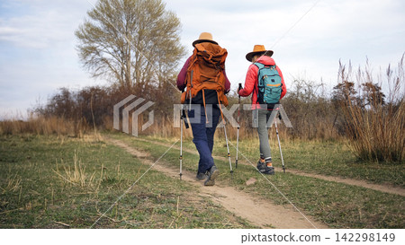 Two travelers with backpacks and trekking poles are traveling to the holy places of the planet. Two lesbians are hiking. Two tourists Two travelers with backpacks and trekking poles are traveling to the holy places of the planet. Two lesbians are hiking. Two tourists 142298149