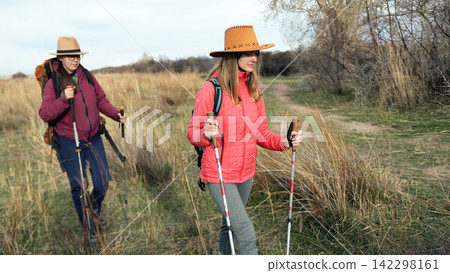 Two active young women are walking in the wilderness. The sisters travel together. Beautiful female students have opened the summer hiking season Two active young women are walking in the wilderness. The sisters travel together. Beautiful female students have opened the summer hiking season 142298161