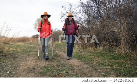 Two athletic women are walking in the woods. Trekking and hiking. Travel, adventure and freedom. The students gathered for a hike 142298168