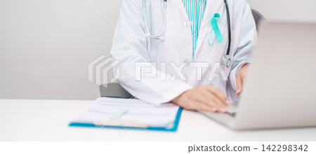 doctor using laptop and report notes on notebook. Teal and white ribbon concept of January Cervical Cancer Awareness month, September Ovarian Cancer, PCOS, April Sexual Assault doctor using laptop and report notes on notebook. Teal and white ribbon concept of January Cervical Cancer Awareness month, September Ovarian Cancer, PCOS, April Sexual Assault 142298342
