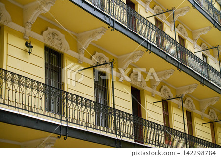 Ornate iron balconies on yellow apartment building facade Ornate iron balconies on yellow apartment building facade 142298784
