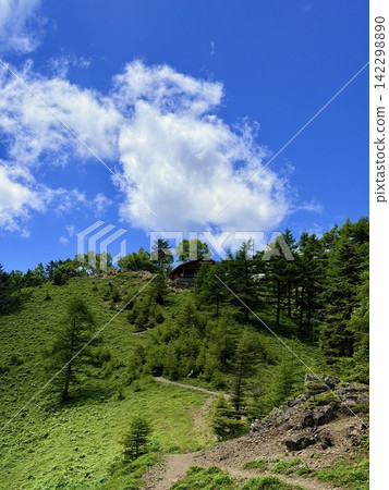 從東京最高峰雲取山頂眺望富士山和夏季山景,周圍環繞著藍天和積雲,以及雲取山避難小屋。 從東京最高峰雲取山頂眺望富士山和夏季山景,周圍環繞著藍天和積雲,以及雲取山避難小屋。 142298890